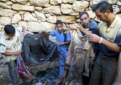 Unos palestinos sostienen la ropa ensangrentada de un líder de la Yihad asesinado en Hebrón.