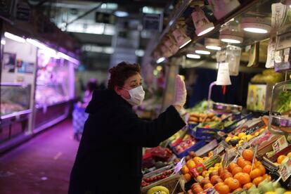 Una mujer se despide del vendedor tras comprar en una frutería de una galería comercial, en Madrid.