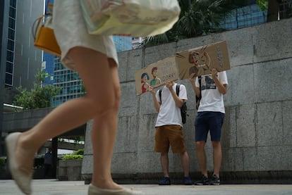 Dos jóvenes sostienen carteles para pedir disculpas por la manifestación del lunes, que impidió el ingreso a una oficina de impuestos del gobierno en Hong Kong por casi dos horas.