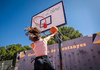Una joven juega a baloncesto en el patio de un colegio. 