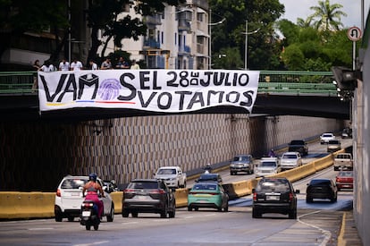 Ciudadanos cuelgan una pancarta sobre una vía automovilista en Caracas, el 24 de julio.