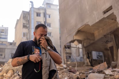 Un familiar sostiene una fotografía de su tío Ali mientras huele una de sus prendas, que sigue desaparecido entre los escombros tras un ataque israelí nocturno, este viernes en Beirut.