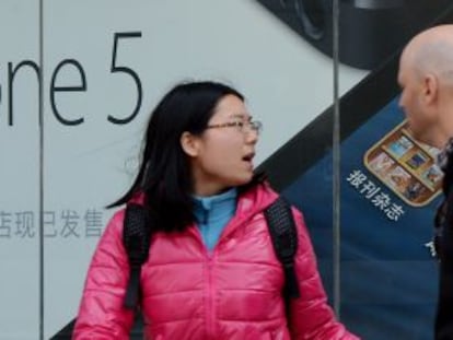 Una pareja camina por delante de una tienda de Apple en Pek&iacute;n (China)