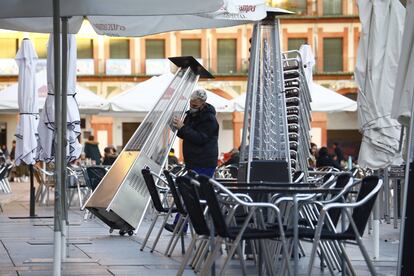 Un trabajador recoge el mobiliario de la terraza de un restaurante en el centro de Córdoba.