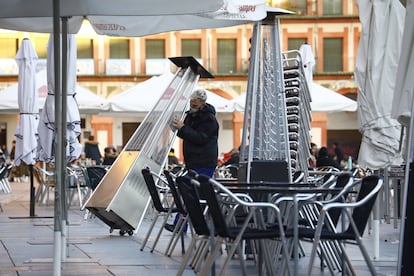 Un trabajador recoge el mobiliario de una terraza en el centro de Córdoba, el lunes, tras entrar en vigor nuevas restricciones en Andalucía.