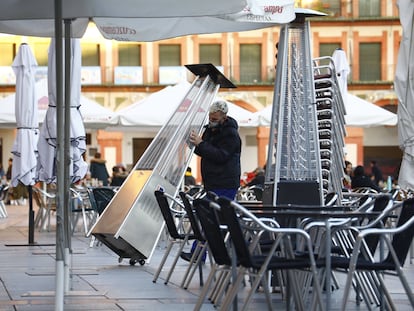 Un trabajador recoge el mobiliario de la terraza de un restaurante en el centro de Córdoba.