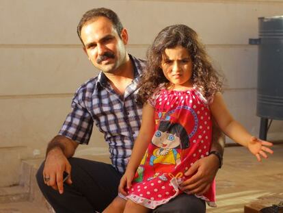 Hassan Ahmed Peraly junto a su hija en la entrada de su casa, en la ciudad iraqu&iacute; de Khanaqin.