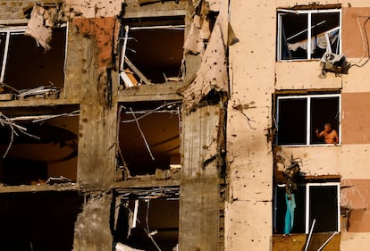 Un residente mira por la ventana de un edificio de apartamentos dañado por un ataque ruso en Kiev.