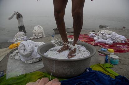 Dos 'dhobis', una de las castas de la India especializadas en el lavado de ropa, trabajan durante una mañana fría y brumosa en Gauhati, en el noreste del estado de Assam.