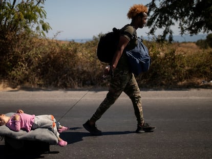 Un migrante arrastra a un bebé por una carretera en Lesbos (Grecia).