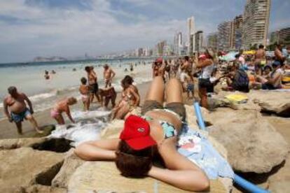 Una turista toma el sol sobre las rocas en la playa de Levante, en Benidorm. EFE/Archivo