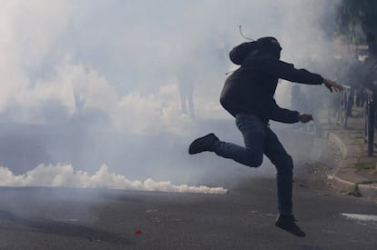 A masked youth runs through a cloud of tear gas during clashes with gendarmes and police during a demonstration against the French labour law proposal in Paris, France, as part of a nationwide labor reform protests and strikes, April 28, 2016.   REUTERS/Philippe Wojazer