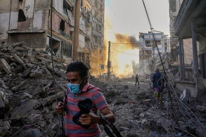 Un fotógrafo corre entre los escombros tras un ataque israelí en el barrio de Dahiyeh en Beirut, este viernes. 