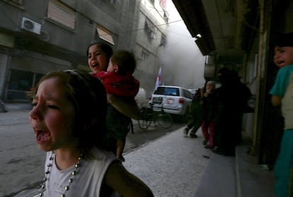 Las niñas Gahazal, de cuatro años; Judy, de siete, y Suhair de ocho meses, corren despavoridas después de un bombardeo por las fuerzas leales al presidente sirio Bachar Al Asad, en el barrio Duma, Damasco.