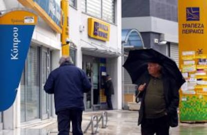 Un hombre pasa junto a una sucursal del Banco de Chipre (i) y del Banco Piraeus (d), en Atenas, Grecia, hoy, jueves 28 de marzo de 2013.