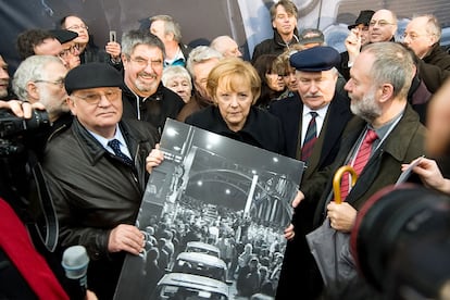 El último líder de la Unión Soviética, Mijaíl Gorbachov (a la izquierda); la canciller alemana, Angela Merkel, y el expresidente polaco, Lech Wałęsa, sostienen una imagen del puente Bösebrücke, el primer paso fronterizo que se abrió en la noche del 9 de noviembre de 1989, durante la caída del muro de Berlín, en una imagen de 2022.