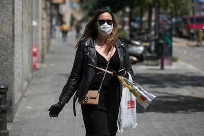 Una dona el dia de Sant Jordi amb mascareta, guants i rosa.