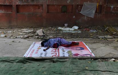 Una mujer duerme en el suelo en una calle de Nueva Delhi (India).