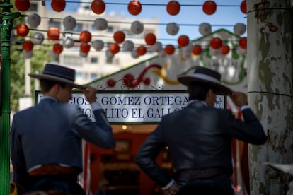 Dos jinetes frente al cartel de la calle del reciento ferial, Joselito El Gallo, dedicadas a toreros, el lunes de Feria en Sevilla. 