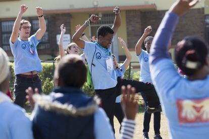 En el centro de la imagen Kabelo Malefane, director del campamento Sizanani, anima a los adolescentes a bailar y cantar a su llegada.