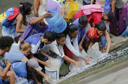 Un grupo de personas recoge agua de la fuga de una tubería en Caracas (Venezuela), el 11 de marzo de 2019.