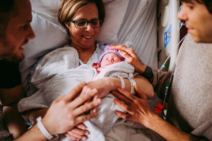 Elliott Dougherty y Matthew Eledge observan a su hija Uma después de que la madre de Matthew, Cecile, dio a luz en el Centro Médico de la Universidad de Nebraska en Omaha, Nebraska, EE UU, el 25 de marzo de 2019.