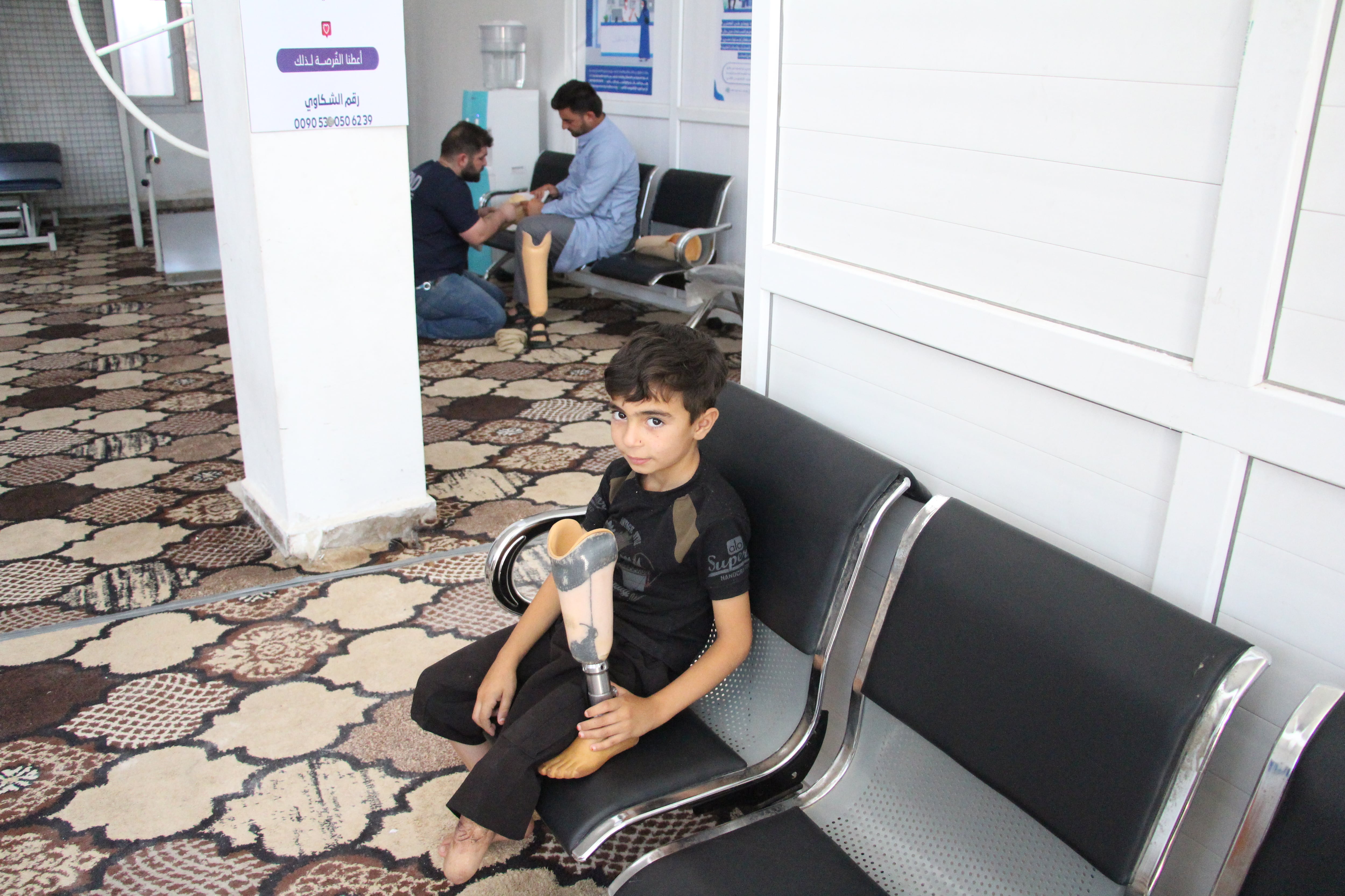 Un niño que perdió su pie por la guerra en Siria posa con su prótesis, en uno de los centros que utiliza impresión 3D en Idlib, en el norte del país, en julio de 2026.