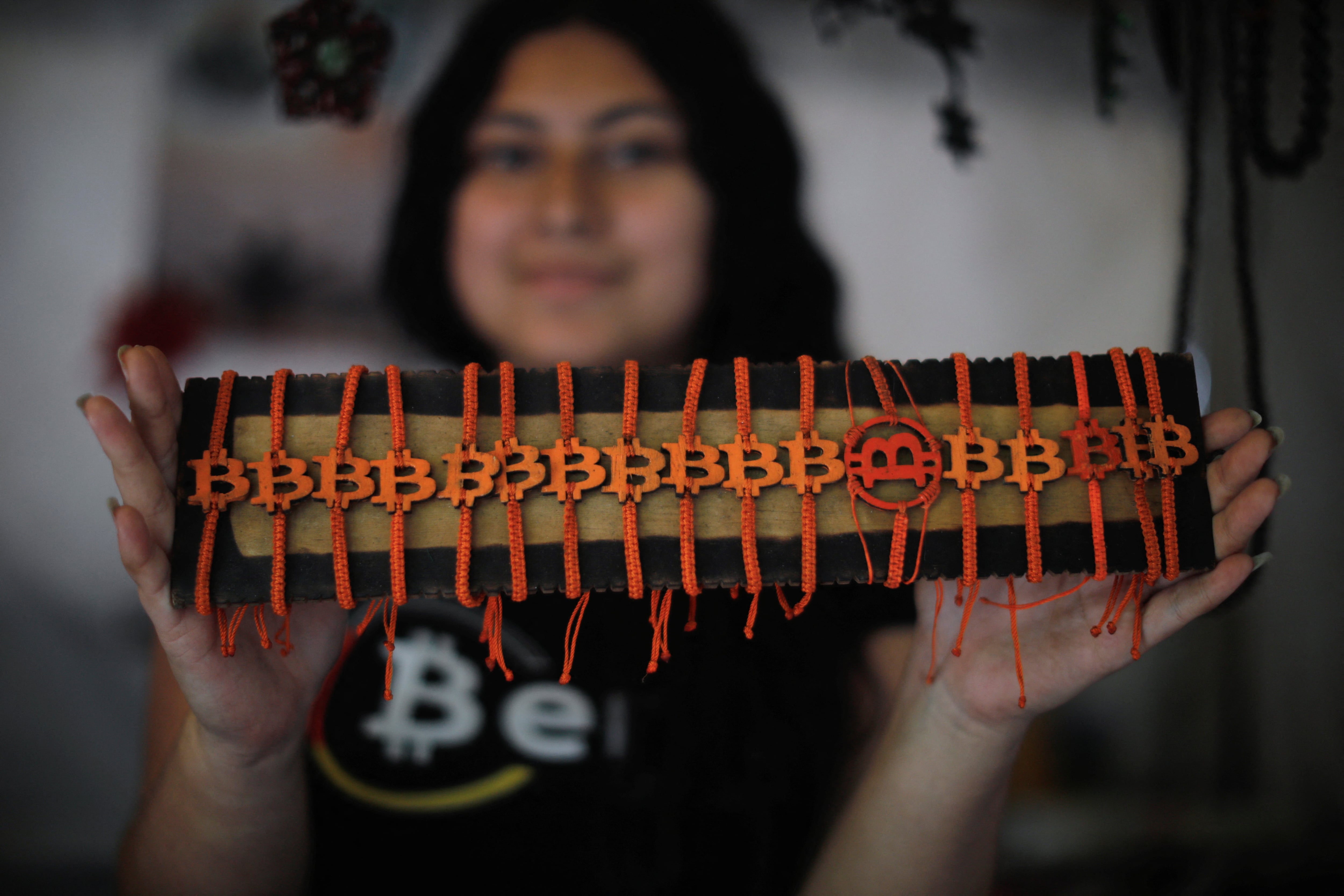 Una mujer enseña unas pulseras con el símbolo de bitcoin. 