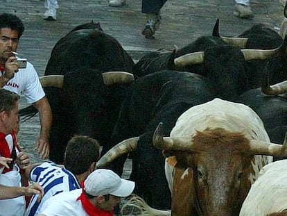 Un mozo, con el pitillo en la boca, la cámara de fotos y un toro detrás, en la cuesta de Santo Domingo durante el encierro de ayer.