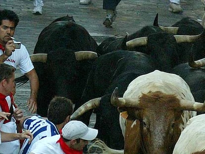 Un mozo, con el pitillo en la boca, la cámara de fotos y un toro detrás, en la cuesta de Santo Domingo durante el encierro de ayer.