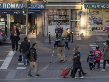 Viandantes cruzan una calle de Usera, en el sur de la ciudad de Madrid.