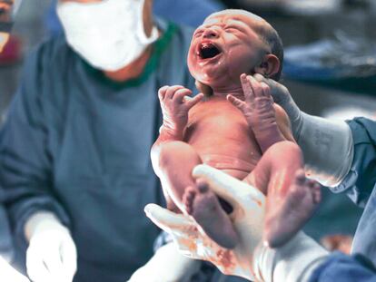 Doctors holding newborn baby boy.