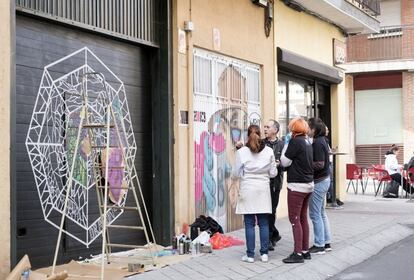 Paco Hidalgo, residente del barrio del Oeste (Salamanca), formó parte de la asociación vecinal ZOES en los ochenta. “Organizábamos partidos de futbito. Entonces había calles de tierra”, recuerda. El asfaltado de las vías y los problemas de suministro de agua explican el nacimiento de ZOES en 1977. “Ahora vienen guías turísticos con grupos de extranjeros. El cambio ha sido espectacular”. La transformación se debe a Galería Urbana, una iniciativa organizada por la asociación en la que artistas urbanos y estudiantes de Bellas Artes llegados de varias partes de España decoran los garajes de los vecinos. Entre el 25 y el 27 del pasado abril se celebró la VIII edición. Hidalgo (en la imagen) comenta la evolución de la vidriera que adornará su cochera con las tres veinteañeras que la han diseñado. Andrea Alonso, Sarah Espinosa y Alba Velázquez, amigas de la universidad, tienen todo pagado en el bar de al lado. Es del primo del propietario del garaje.