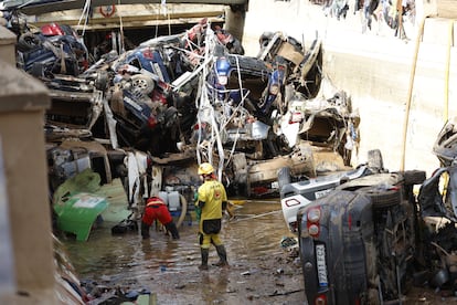 Dos bomberos achican agua con una bomba ante una pila de coches en un túnel de Benetússer (Valencia), este viernes.