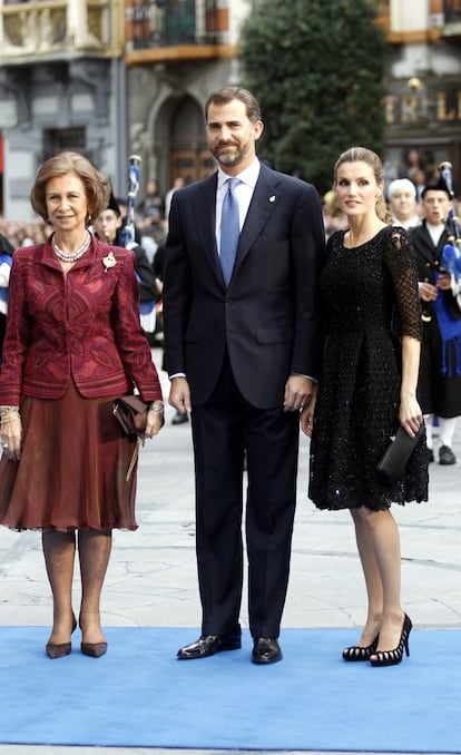 En la edición de 2010 de los premios Príncipe de Asturias, doña Letizia apostó de nuevo por el color negro con toques brillantes en su traje, y llevó el pelo recogido en una coleta. En la foto, con don Felipe y doña Sofía.