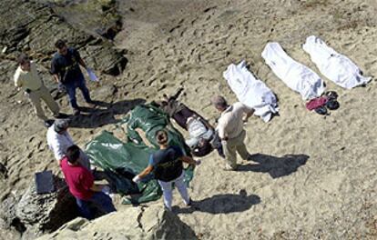 Agentes de la Guarcia Civil preparan seis de los trece cadáveres localizados en una playa de Tarifa para su traslado al cementerio de Algeciras.