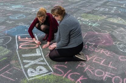 Dues persones escriuen missatges de solidaritat amb guix davant de la Borsa de Brussel·les.