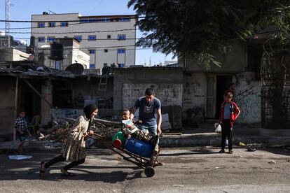 Una joven empuja un carro con bidones llenos de agua mientras un niño se mantiene sobre ellos, este viernes en Rafah. 