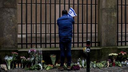 Un hombre pone una bandera israel&iacute; en la sinagoga de Copenhague.