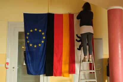 Una trabajadora coloca las banderas de la Unión Europea y de Alemania momentos antes de abrir un centro electoral en Berlín (Alemania).