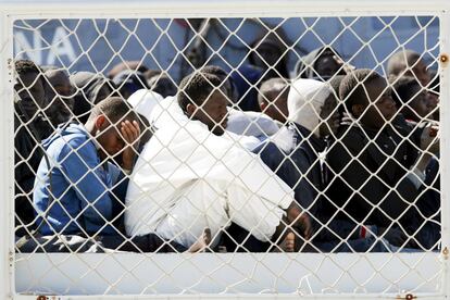 Migrantes esperan para desembarcar de un buque de la marina italiana, en el puerto siciliano de Augusta (Italia).