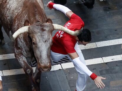 PAMPLONA, 13/07/2022.- Un mozo pasa rozando a un astado durante el séptimo encierro de los Sanfermines ante los toros de la ganadería de Victoriano del Río Cortés, este miércoles en Pamplona. EFE/Jesus Diges
