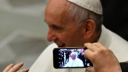 Uma pessoa tira uma foto do papa Francisco no Vaticano.