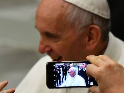 Uma pessoa tira uma foto do papa Francisco no Vaticano.