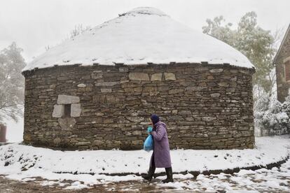 Una mujer camina bien abrigada en el alto de O Cebreiro (Lugo), que ha amanecido cubierto por la nieve y donde se acusa un brusco descenso de las temperaturas.