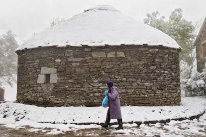 Una mujer camina bien abrigada en el alto de O Cebreiro (Lugo), que ha amanecido cubierto por la nieve y donde se acusa un brusco descenso de las temperaturas.