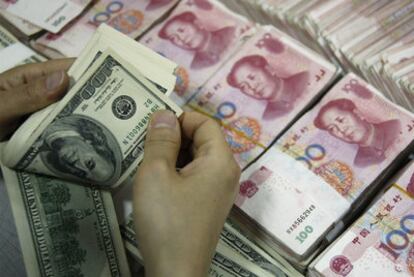Un empleado de un banco chino cuenta dólares y yuanes.