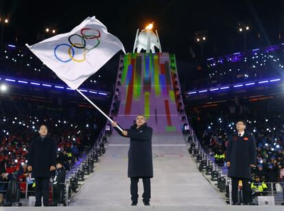 El presidente del Comité Olímpico Internacional, Thomas Bach (c), junto a los alcaldes de PyeongChang, Sim Jae-guk y Pekín, Chen Jining, participan en la entrega de la bandera olímpica durante la ceremonia de clausura, el 25 de febrero de 2018.