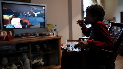 Un niño come un trozo de pizza  mientras ve la televisión en Madrid.