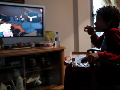 Un niño come un trozo de pizza mientras ve la televisión.